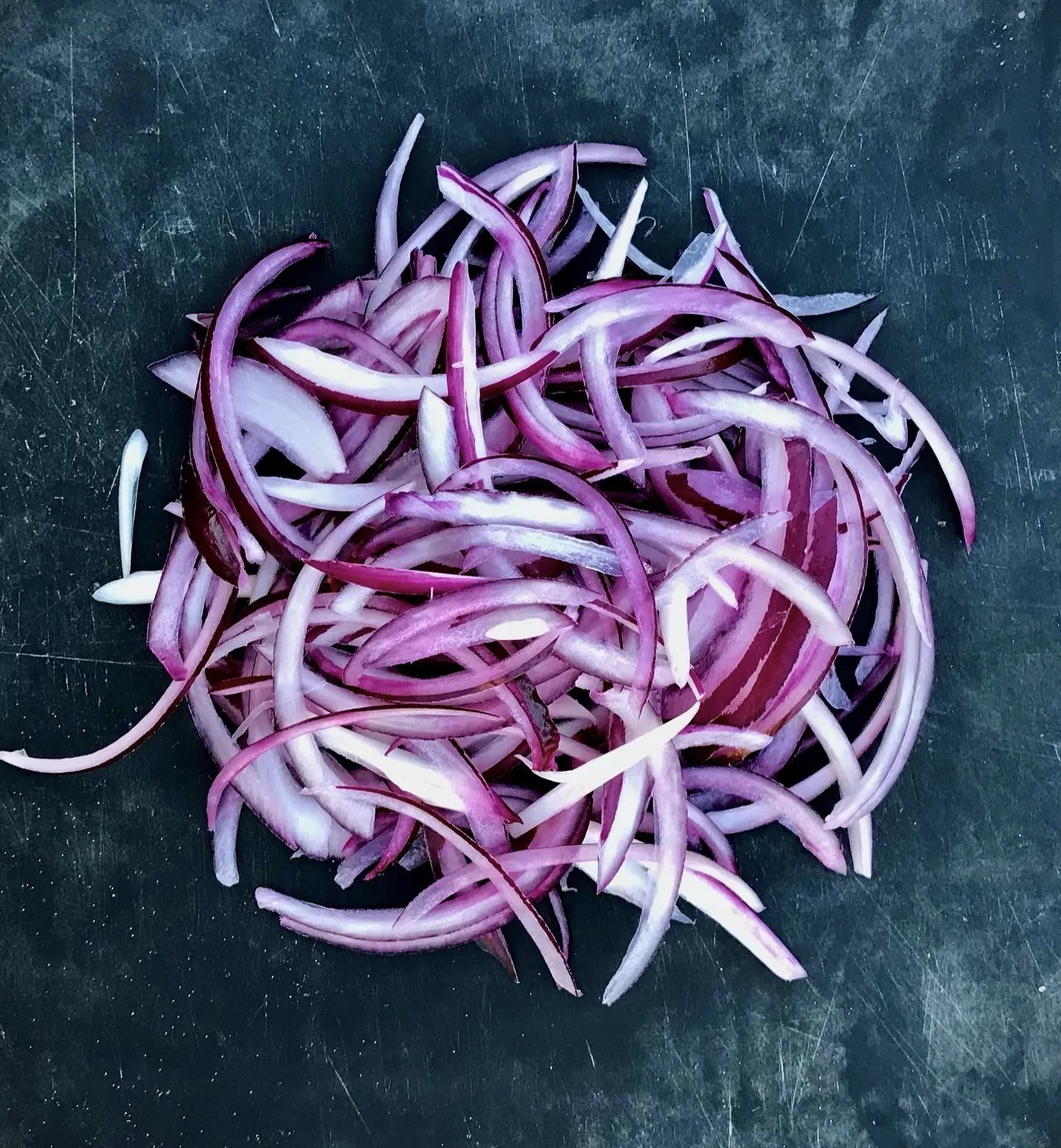Oignons rouges émincés à la main sur une planche noire professionnelle dans la pizzeria PIZZAPP à Salon-de-Provence.